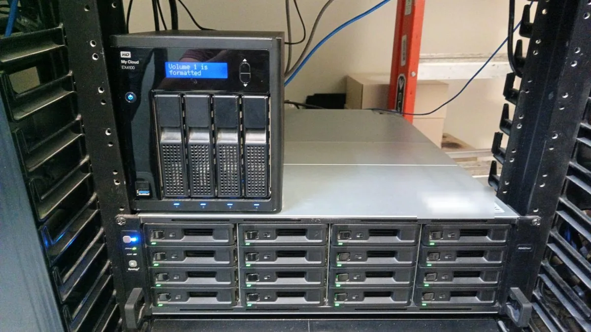 Dos equipos de respaldo montados en rack: un NAS de cuatro bahías sobre otro de dieciséis, con los discos en verde