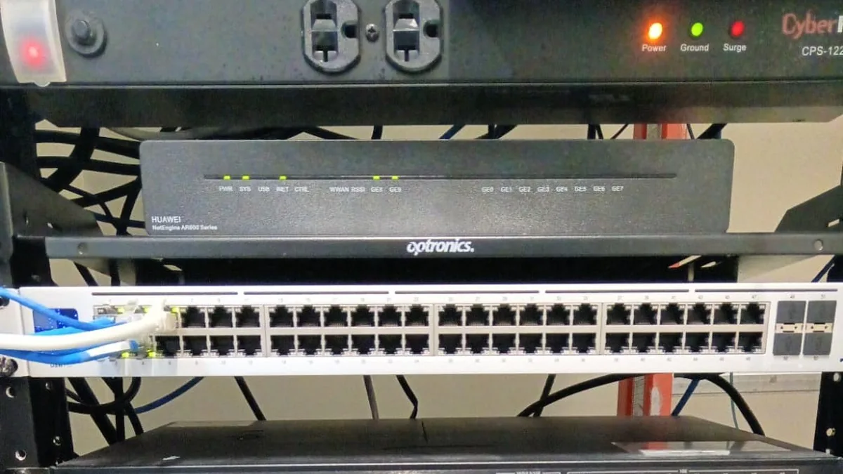 Parte alta de un rack de comunicaciones: barra de contactos, router empresarial y switch administrable de 48 puertos